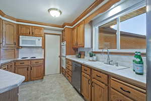 Kitchen featuring brown cabinets, white appliances, backsplash, and ornamental molding