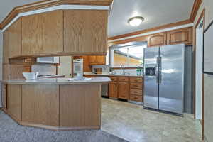 Kitchen featuring stainless steel appliances, brown cabinets, tasteful backsplash, a peninsula, and crown molding