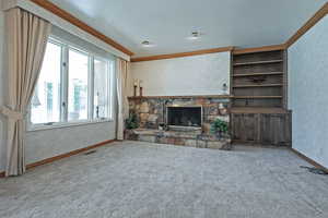 Unfurnished living room with crown molding, a stone fireplace, and carpet flooring