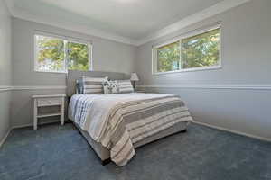 Bedroom featuring multiple windows, ornamental molding, and carpet flooring