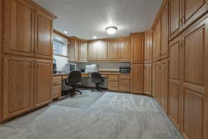 Home office featuring built in desk, light carpet, and recessed lighting