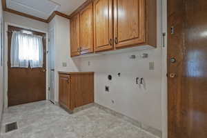 Laundry area featuring gas dryer hookup, crown molding, cabinet space, hookup for an electric dryer, and hookup for a washing machine