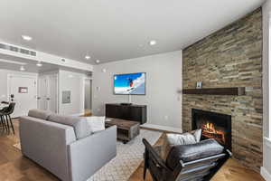 Living area with wood finished floors, recessed lighting, a stone fireplace, and electric panel
