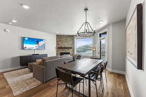 Dining room with a fireplace, wood finished floors, a chandelier, and recessed lighting