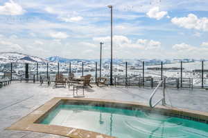 Snow covered pool with a swimming pool, a mountain view, and a patio area