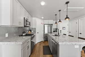 Kitchen featuring a breakfast bar area, stainless steel appliances, backsplash, a center island with sink, and recessed lighting