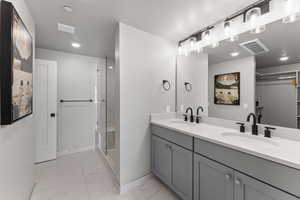 Full bathroom with double vanity, a marble finish shower, light marble finish floors, recessed lighting, and a closet