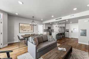 Living area with a chandelier, dark wood-style floors, electric panel, and recessed lighting