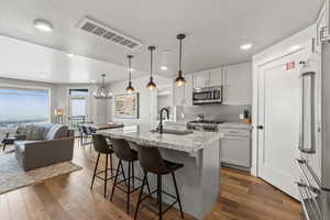 Kitchen featuring backsplash, an island with sink, dark wood-type flooring, stainless steel appliances, and recessed lighting