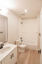 Full bathroom with a textured ceiling, vanity, light wood finished floors, and bathtub / shower combination
