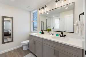 Ensuite bathroom featuring light wood-style floors, double vanity, a shower stall, and recessed lighting
