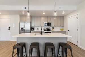 Kitchen with gray cabinetry, tasteful backsplash, decorative light fixtures, stainless steel appliances, and recessed lighting
