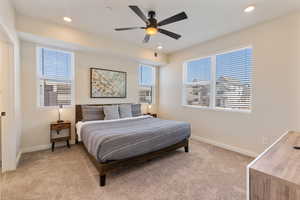 Bedroom with multiple windows, light colored carpet, a ceiling fan, and recessed lighting