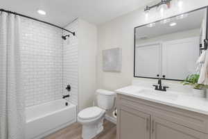 Bathroom with shower / bath combo with shower curtain, light wood-type flooring, vanity, recessed lighting, and a textured ceiling
