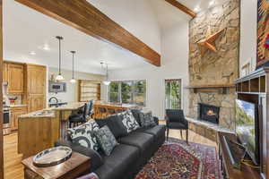 Living room with beam ceiling, light wood-style floors, a fireplace, recessed lighting, and high vaulted ceiling
