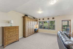 Living area featuring light carpet, built in desk, and a textured ceiling