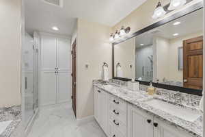 Bathroom featuring a marble finish shower, double vanity, recessed lighting, and light marble finish flooring