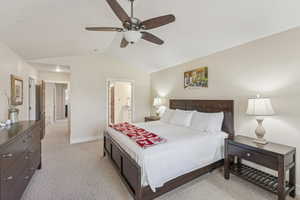 Bedroom featuring vaulted ceiling, light carpet, a ceiling fan, and ensuite bathroom
