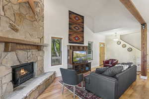 Living room with wood finished floors, high vaulted ceiling, a fireplace, and stairs