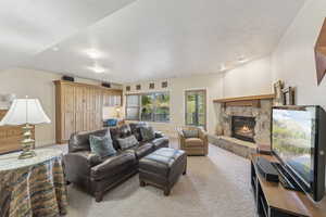Living room featuring light carpet, a fireplace, and a textured ceiling