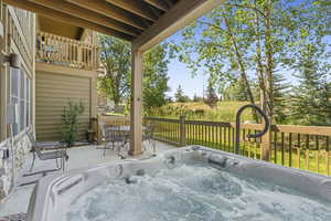 Wooden deck featuring a hot tub, outdoor dining area, and a patio