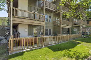 Back of house with board and batten siding, a patio, a yard, and a balcony
