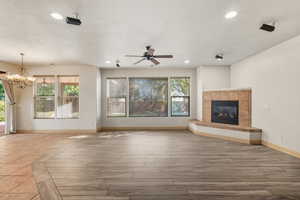 Unfurnished living room featuring a tiled fireplace, recessed lighting, a chandelier, wood finished floors, and ceiling fan