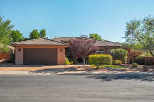 Single story home featuring stucco siding, a tiled roof, driveway, and an attached garage