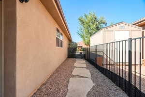 View of side of property featuring a gate, a shed, and stucco siding