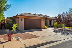 Ranch-style home featuring concrete driveway, stucco siding, a tiled roof, and an attached garage