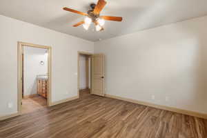 Unfurnished bedroom with light wood-style flooring, ceiling fan, and ensuite bathroom