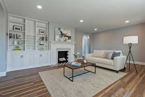 Living room featuring arched walkways, recessed lighting, a fireplace, and dark wood-style flooring