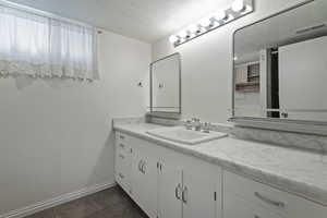 Bathroom with vanity, a textured ceiling, and dark tile patterned floors