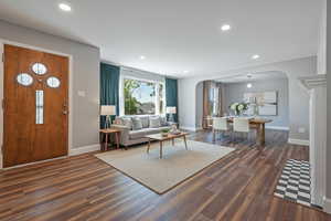 Living room with arched walkways, recessed lighting, and dark wood-style floors