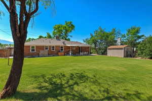 Rear view of property featuring a patio area, a shed, entry steps, a chimney, and brick siding