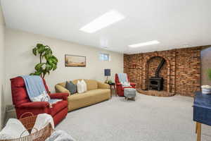 Living area featuring a wood stove, carpet, and brick wall