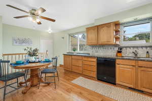 Kitchen featuring brown cabinets, backsplash, dishwasher, light wood finished floors, and dark stone counters