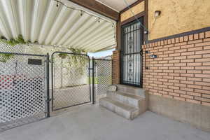 View of exterior entry with a gate and stucco siding