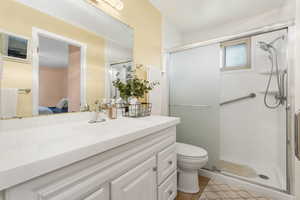 Bathroom featuring a shower stall, vanity, ensuite bathroom, and light tile flooring