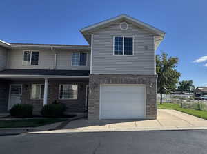 Traditional-style home with covered porch, a garage, brick siding, and concrete driveway