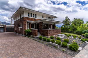 View of front of property with brick siding, a garage, and covered porch