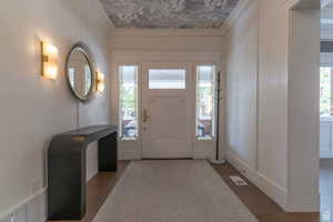 Foyer entrance with ornamental molding, light wood-style flooring, and healthy amount of natural light