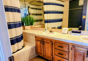 Full bathroom with double vanity, light tile patterned floors, and shower / tub combo with curtain
