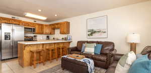 Kitchen featuring a peninsula, appliances with stainless steel finishes, brown cabinets, open floor plan, and a breakfast bar area