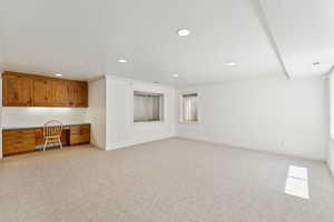 Unfurnished living room featuring built in study area, light carpet, and recessed lighting