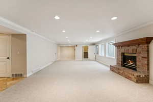 Unfurnished living room featuring ornamental molding, recessed lighting, a brick fireplace, and light colored carpet