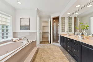 Bathroom featuring crown molding, a shower stall, double vanity, a bath, and recessed lighting