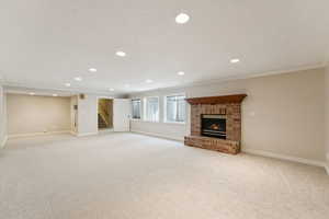 Unfurnished living room featuring recessed lighting, light carpet, a brick fireplace, stairs, and crown molding