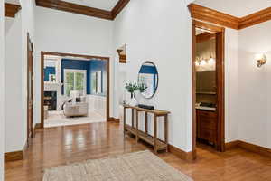 Hallway featuring light wood-style flooring, ornamental molding, and a high ceiling