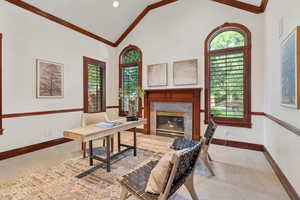 Office area featuring a fireplace, crown molding, light colored carpet, and high vaulted ceiling